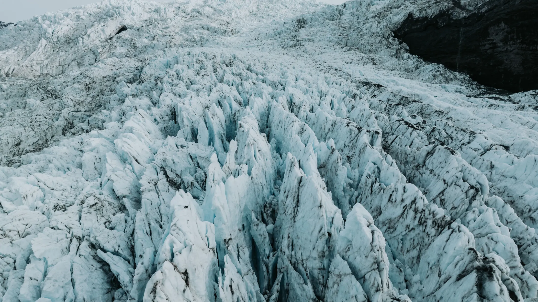 The ice fall on Falljökull glacier consists of large, blue-tinted spiky formations of glacier ice.