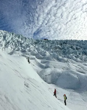 A client on an ice climbing tour reaches the top of a glacial wall on Falljökull.