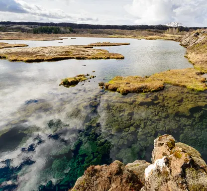 Clouds reflect on the deep, vibrant blue-green water of Silfra at the edge of Lake Thingvallavatn.