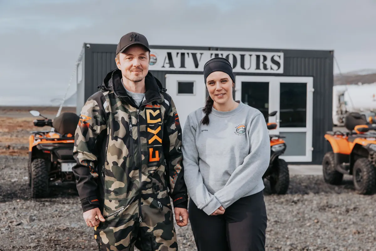 The smiling owners stand in front of their ATV operation.