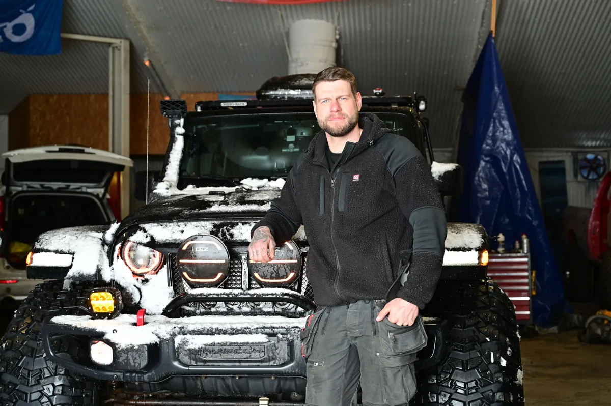 An Icelandic guide stands in a garage in front of his self-built super jeep.