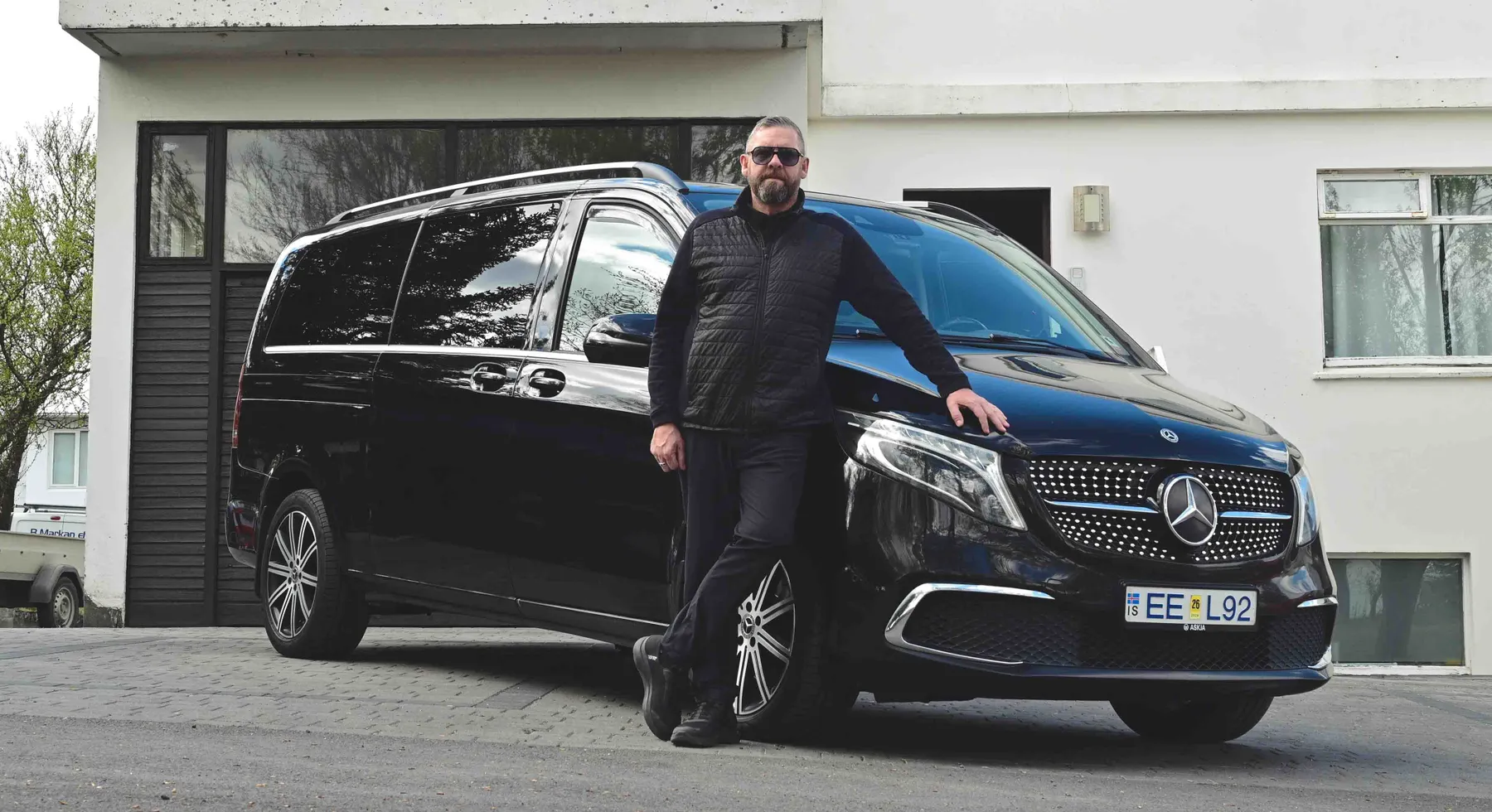 A local Icelandic guide standing in front of his shiny black Mercedes van.