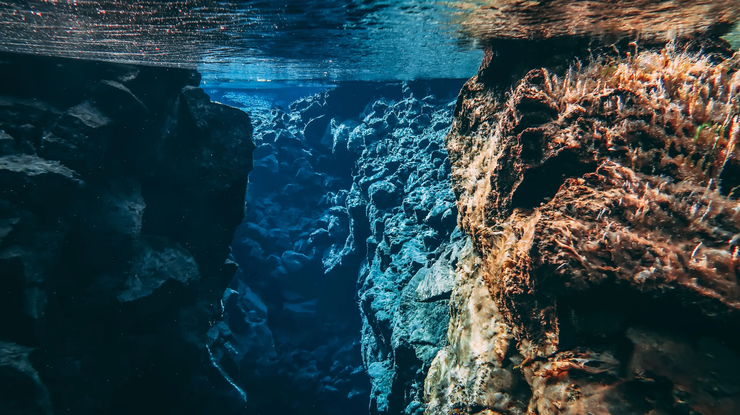 Sun shines into the Silfra fissure, illuminating the bright blue water.