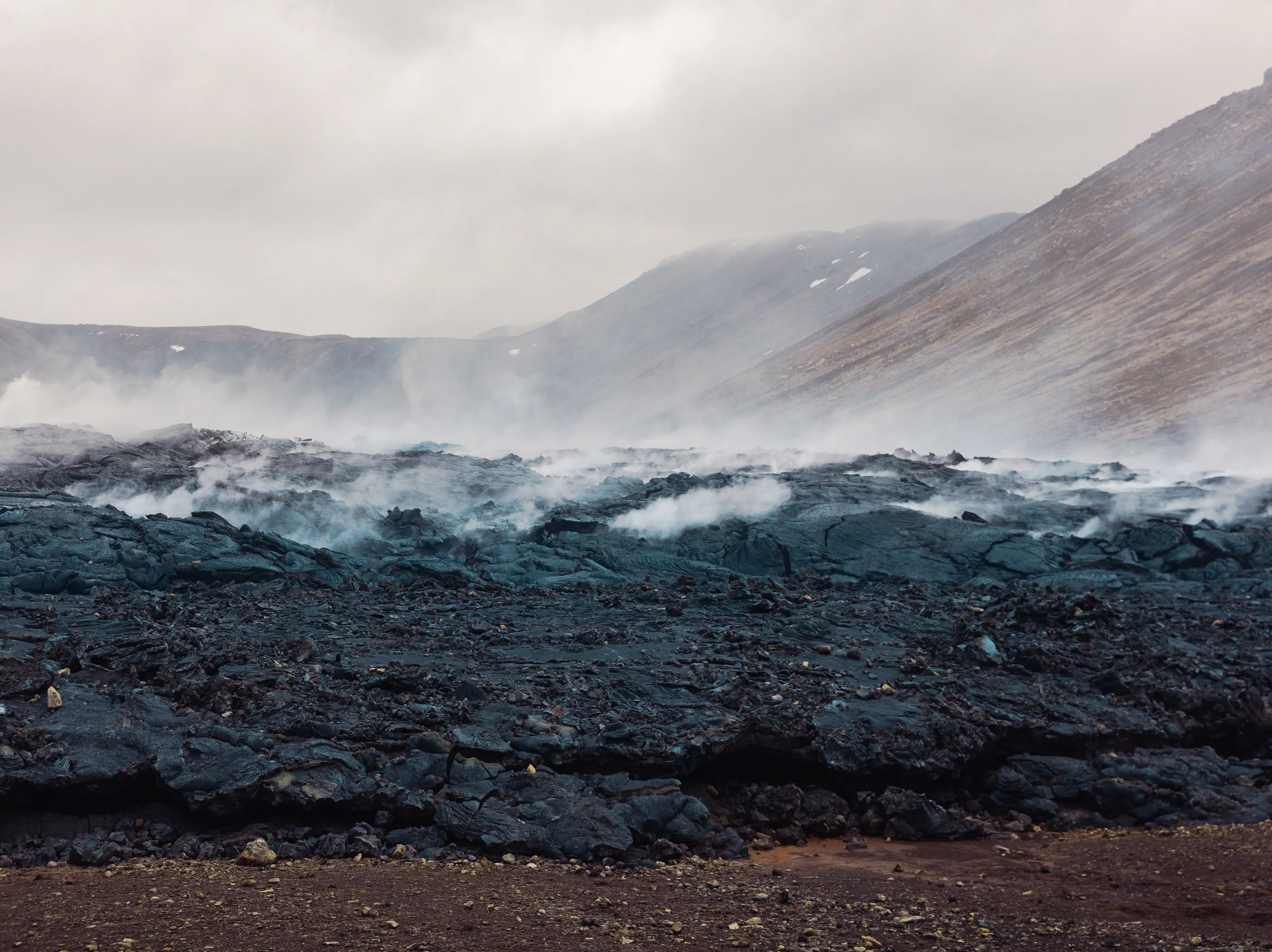 Steam emanates from deep, black lava, still cooling off from a recent volcanic eruption on Iceland's Reykjanes Peninsula.