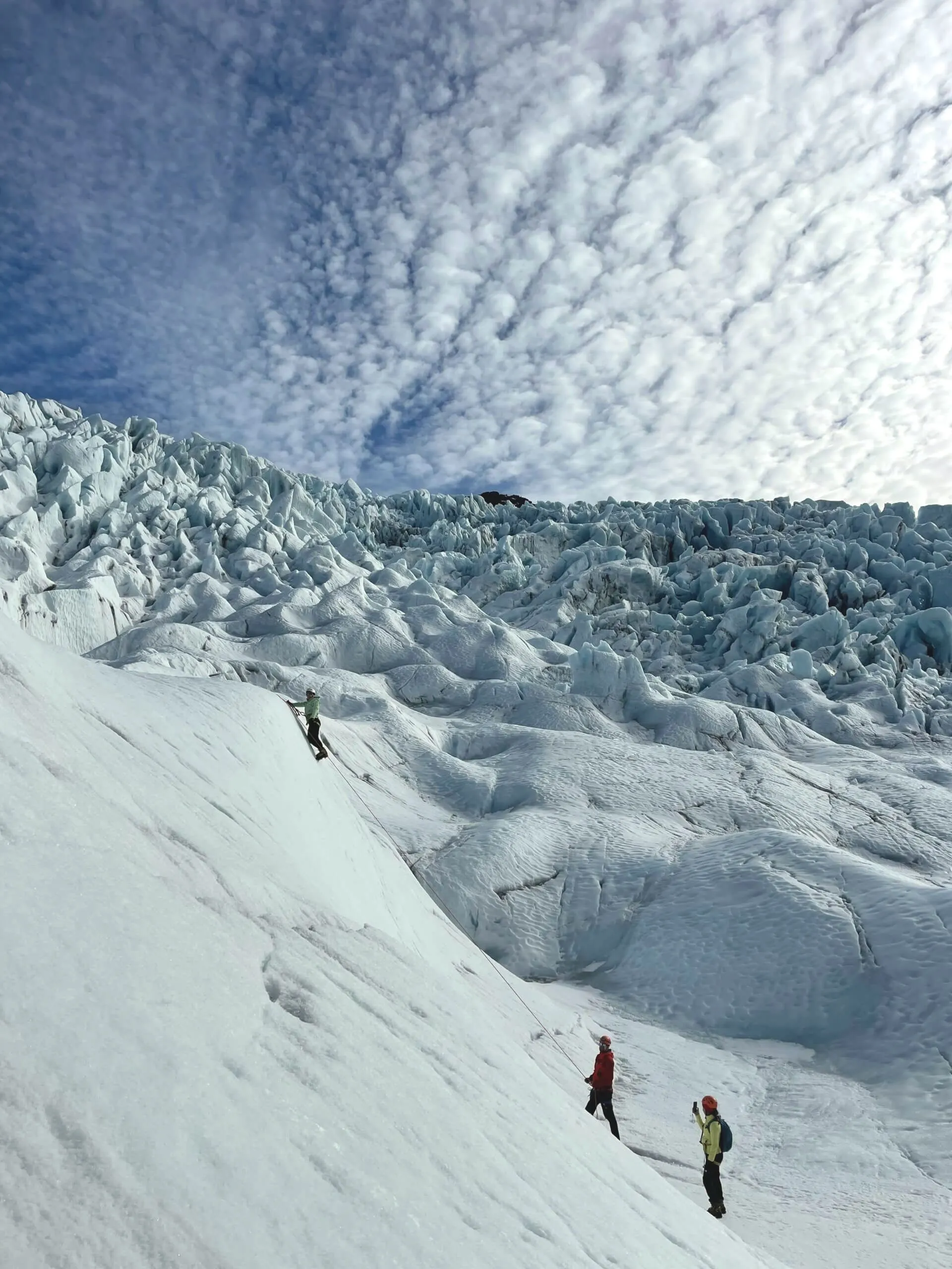 A client on an ice climbing tour reaches the top of a glacial wall on Falljökull. 