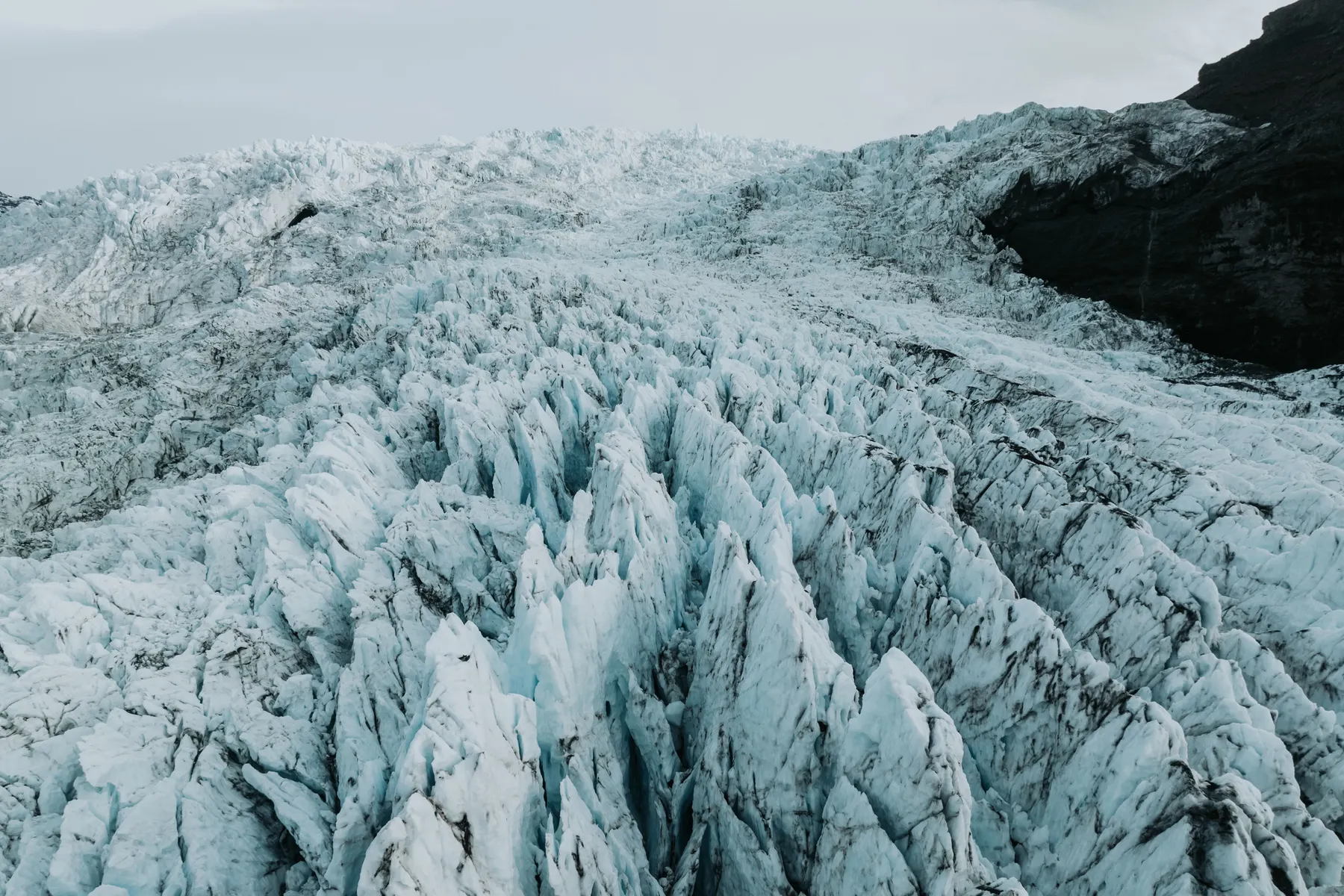 The ice fall on Falljökull glacier consists of large, blue-tinted spiky formations of glacier ice.